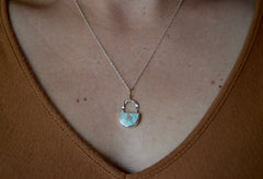 Light blue crescent shaped sand hill turquoise pendant with twisted wire and 18k gold bail. Worn on neck.