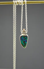 Necklace with a very colorful Australian boulder opal with blues and greens in it. Rose gold dot detail on top. On a silver chain