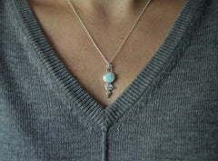  celestial pendant necklace with round blue turquoise, mixed metal dot planets and star shaped bail. On a silver chain. Shown on a model with gray sweater