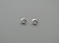 Silver ladybug stud earrings on gray background
