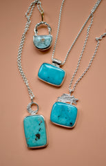 Different turquoise necklaces laid out on an orange background.