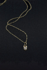 Thin gold chain on a black background with a tiny star shaped pendant that contains a small diamond.