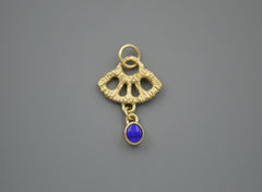 Gold textured fan shape charm with a dark blue opal dangling from the bottom