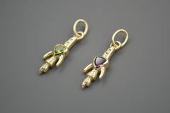 Gold rocket ship pendants with gemstones on a gray background