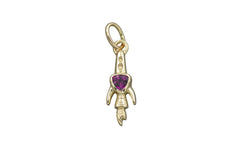 Gold rocket ship pendant with a purple trillion gemstone on a gray background