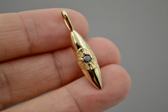14k gold eye pendant that hangs vertically. The pupil of the eye is a faceted black diamond. Shown laying on a hand.