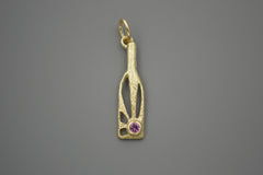 Gold bottle shaped pendant with sun rays within and pink gemstone