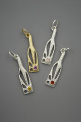 Three silver and one gold bottle-shaped pendants with sunshine rays within and gemstones on gray