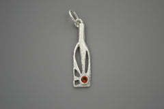Silver bottle shaped pendant with sun rays within and orangey red gemstone