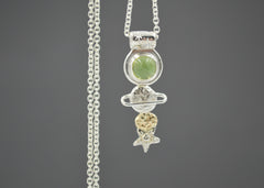  Celestial necklace with stars and planet shapes in silver and gold and a green peridot gemstone.