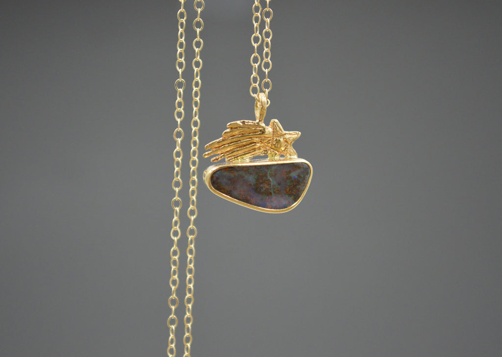 Gold Necklace with a shooting star sitting on top of an Australian boulder opal on a gray background