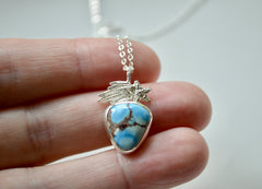Silver Golden Hills Turquoise Necklace with a shooting star. Placed on fingertips