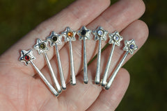Silver and 14K Star Wand Pendants on a hand each with a different colored gemstone.