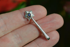 Silver and 14k star wand pendant with a purpley blue iolite gemstone on fingertips
