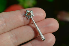 Silver and 14k star wand pendant with an orangey yellow gemstone on fingertips
