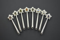 Silver and 14K Star Wand Pendants on a gray background each with a different colored gemstone.
