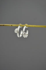 Sterling silver Ladybug Hoop earrings hanging from a rod. Gray background