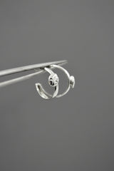 mismatching sterling silver ladybug hoop earrings being held by a tweezer