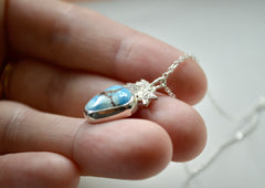 Silver Golden Hills Turquoise Necklace with a shooting star. Side view on fingertips