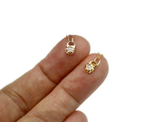 Tiny gold pendants shown on fingertips to show how small they are. Small pendants are star shaped with small diamonds within.