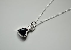 A black onyx heart with a star on top of it and a textured bail. Necklace is sterling silver.