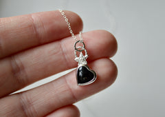 A black onyx heart with a star on top of it and a textured bail. Necklace is sterling silver. On hand for size comparison.