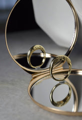 Shows the Night and Day Two Sided Ring in a mirror showing the reflection of the other side of the ring. One side shows the rising sun and the other shows a crescent moon and stars.
