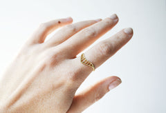 Intricate gold chevron ring on hand