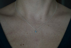 Silver Necklace with a tiny star pendant and a blue sapphire set within worn on a model