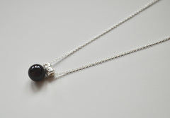 black onyx sphere hangs from a star encrusted pendant on a sterling silver chain.