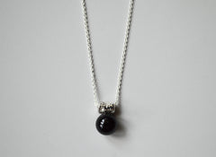 black onyx sphere hangs from a star encrusted pendant on a sterling silver chain.