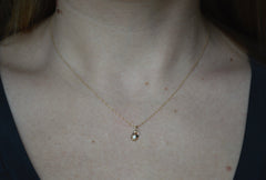 Photo of a neck wearing a thin gold necklace with a tiny pendant that is star shaped with a diamond within